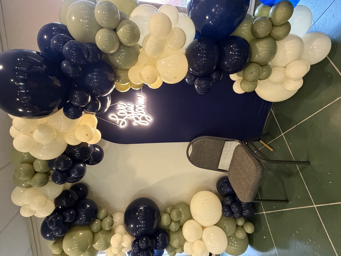 Navy and sage balloon arch with neon sign