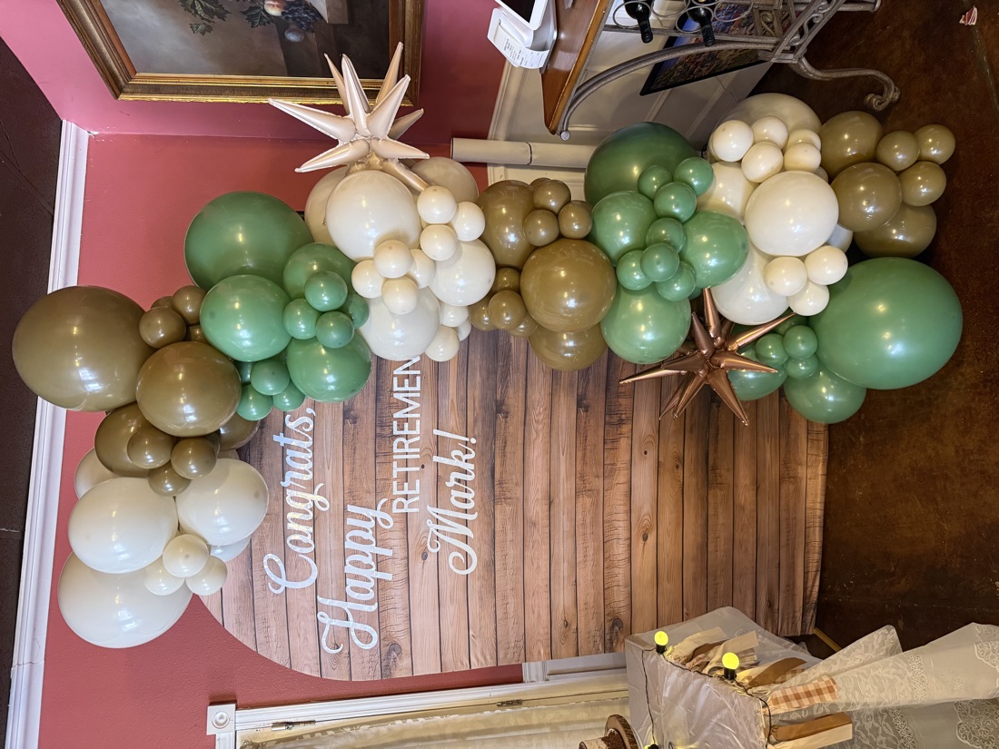 Sage and tan balloon arch on a wood backdrop